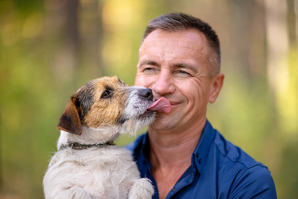 A man smiling with his dog outside